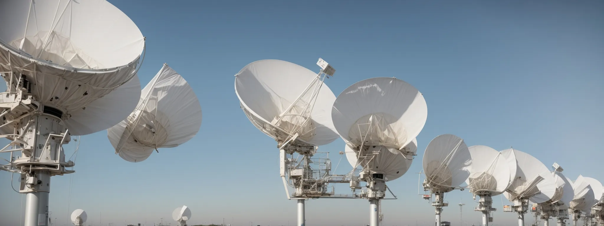 a row of satellite dishes representing media outlets waits under a clear sky, symbolizing the network of press release distribution channels.