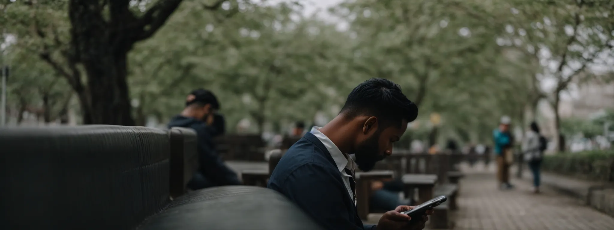 a person sitting on a bench absorbed in using a smartphone, with a clear, unfocused background.