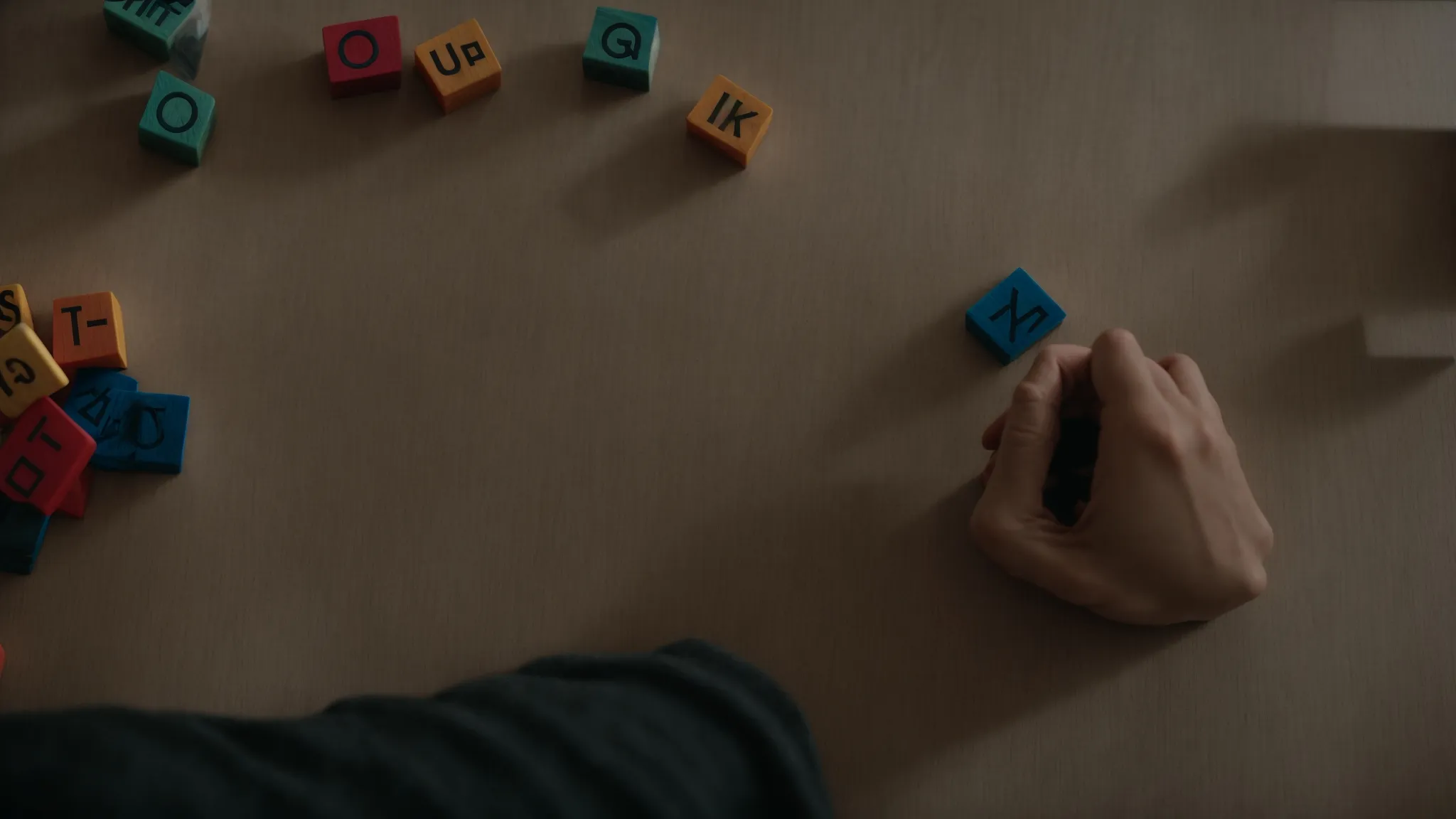 a person thoughtfully arranging alphabet blocks on a table to form a web address.