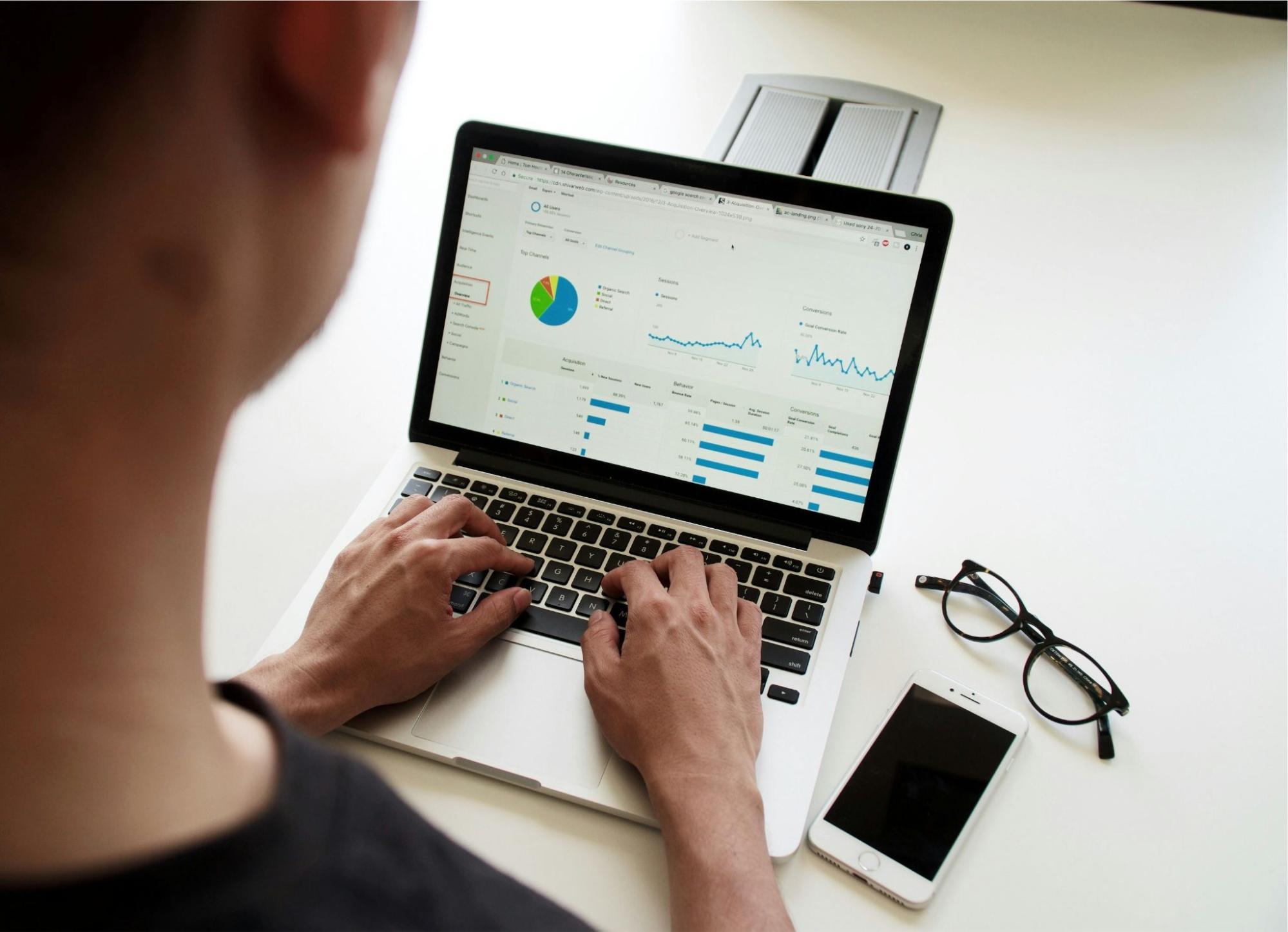 A person analyzing data on SEO competition analysis software, with graphs, charts, and performance metrics displayed on the laptop screen. 