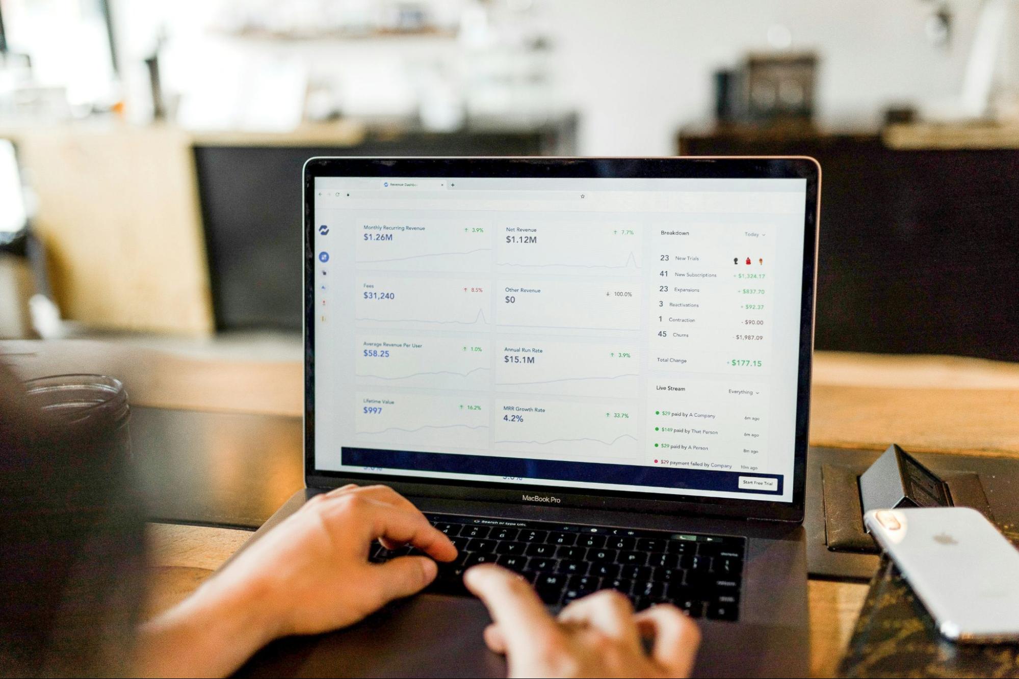 A person using SEO competition analysis software on a laptop with various metrics and performance indicators displayed on the screen