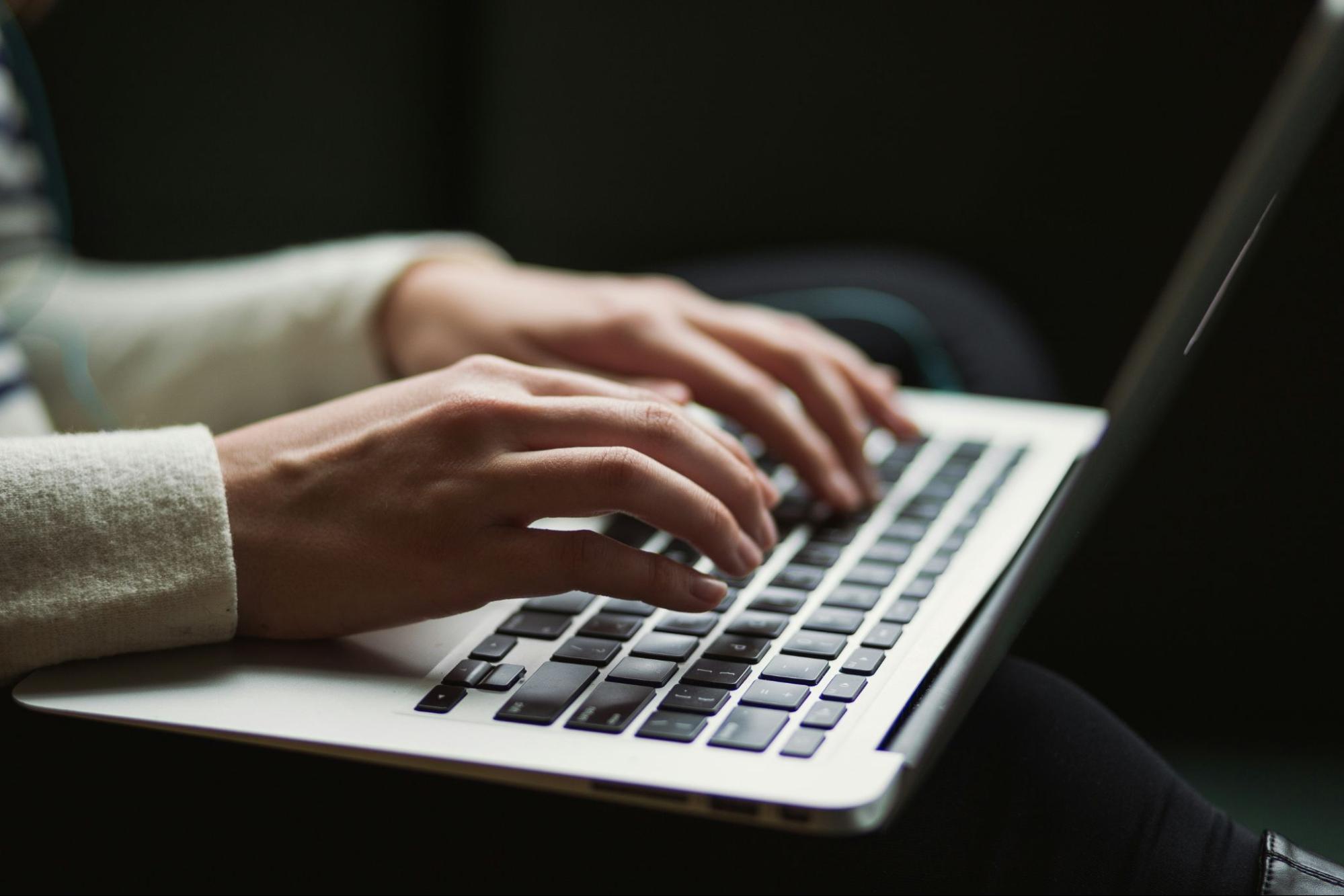 Hands typing on a laptop keyboard, symbolizing content creation, SEO research, and outbound link building for SEO strategy and improving search engine rankings.