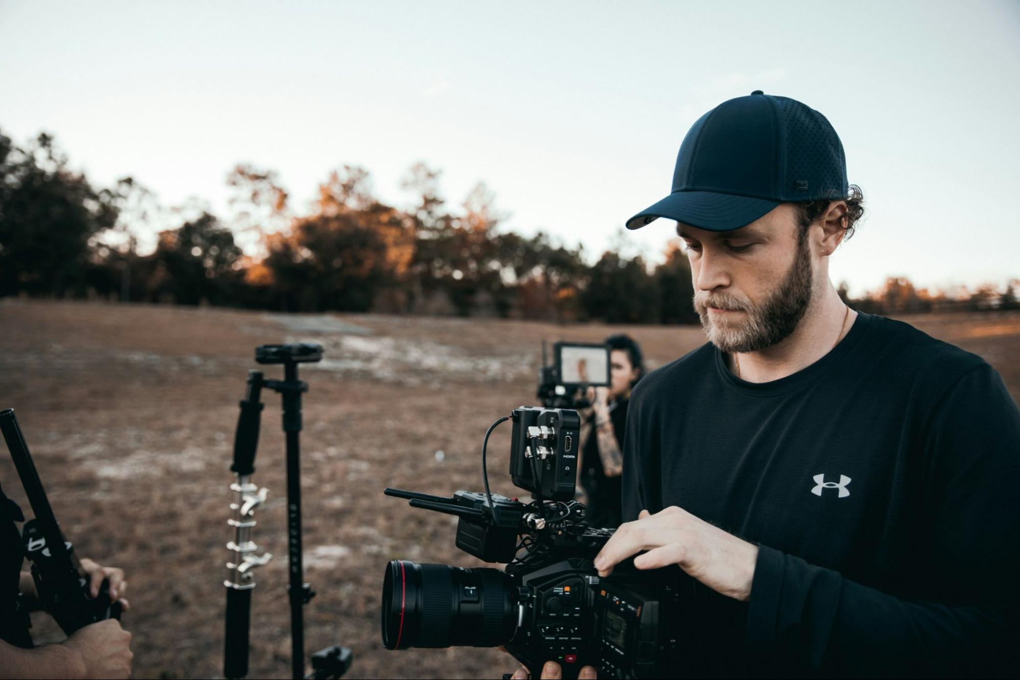 Photographer adjusting a camera outdoors, representing the importance of SEO services for photographers to increase visibility and attract clients